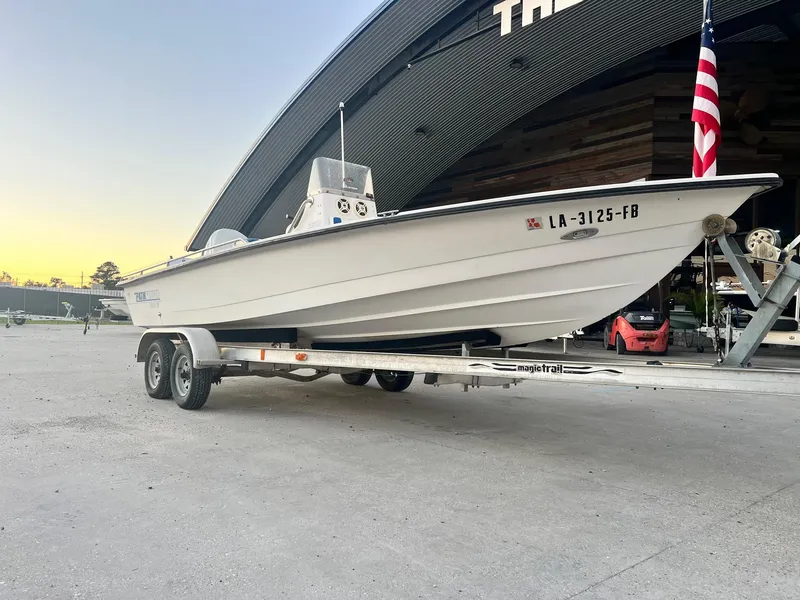 Slide: The Image of 2000 Pathfinder 2200 boat on trailer, parked near a large building at sunset. - 7