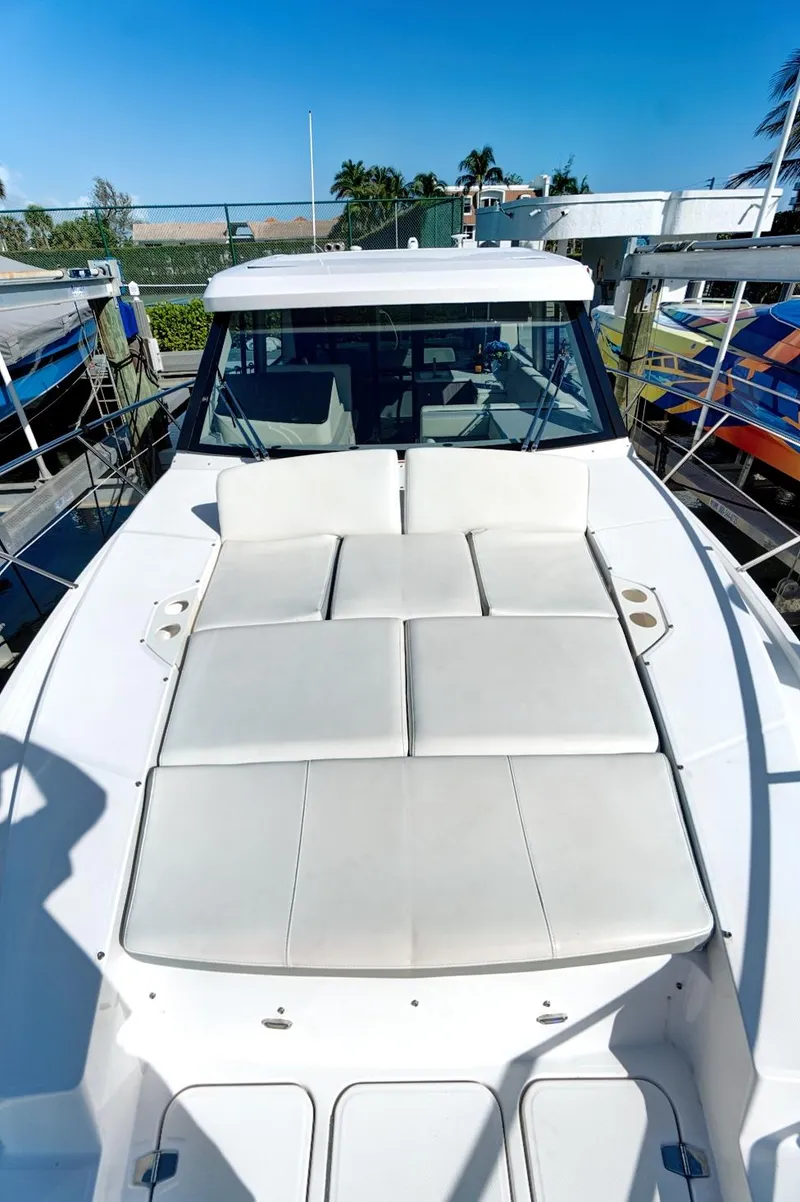 Slide: The Image of 2022 Regal 38 XO yacht with spacious sunbathing deck, docked under clear blue sky. - 11