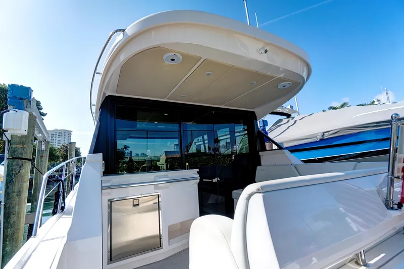Slide: The Image of 2022 Regal 38 XO yacht, rear view, docked under clear blue sky. - 12