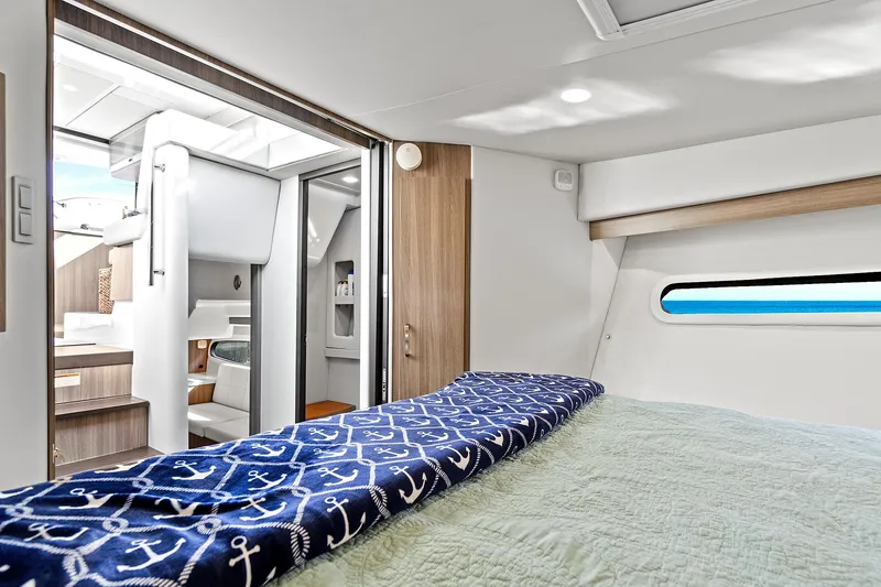 Slide: The Image of Interior of 2022 Regal 38 XO yacht, featuring a cozy bedroom with nautical-themed decor. - 35