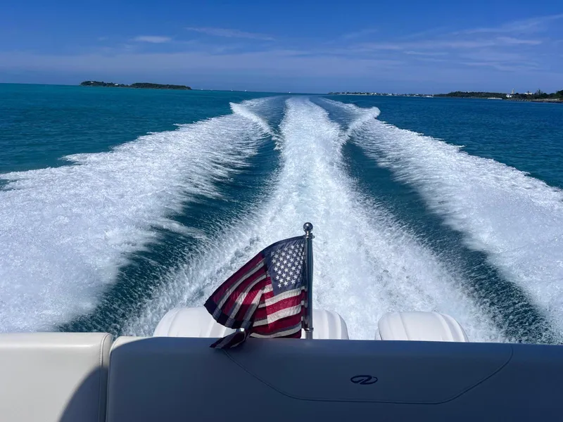 Slide: The Image of 2022 Regal 38 XO cruising, leaving a wake in turquoise waters with an American flag. - 4