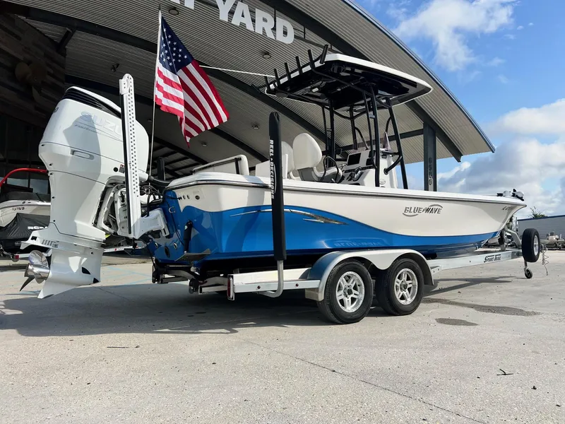 Slide: The Image of 2021 Blue Wave 2400 PURE BAY boat on trailer, American flag, outdoor display. - 11
