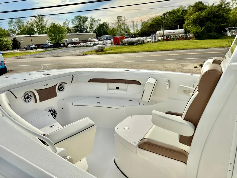 Slide: The Image of 2025 Tidewater 256 LXF boat interior with seating and speakers, parked near a road. - 19