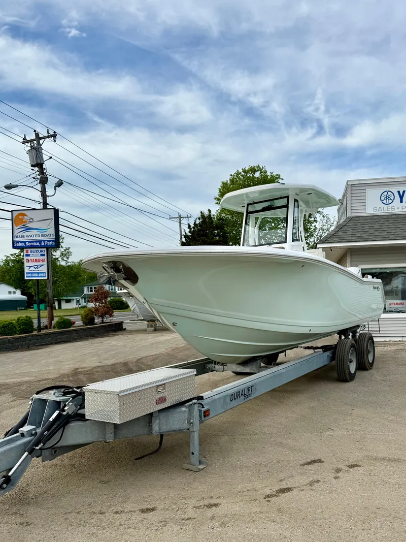 Slide: The Image of 2025 Tidewater 256 LXF boat on trailer, parked outdoors under a cloudy sky. - 8