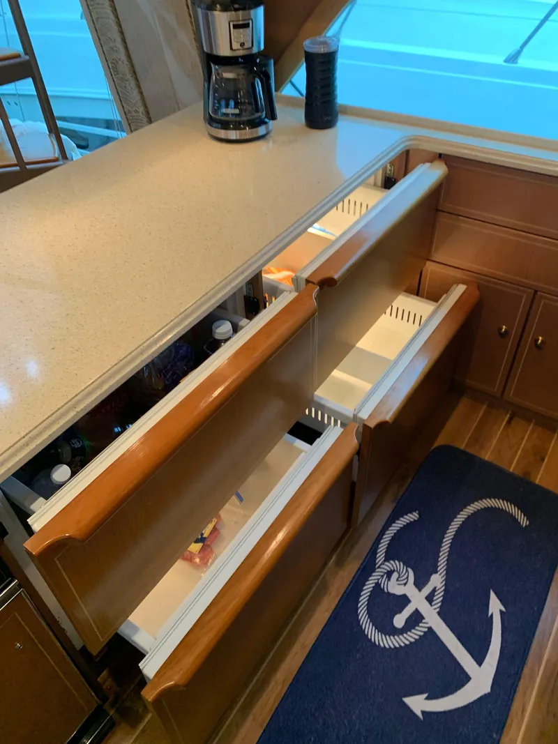 Slide: The Image of 2004 Ocean Yachts 57 Odyssey kitchen with open drawers and anchor-themed rug. - 21