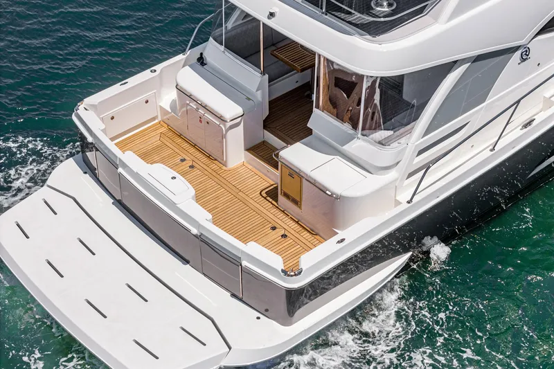 Slide: The Image of 2025 Riviera 46 Sport Motor Yacht with spacious deck cruising on clear waters. - 14