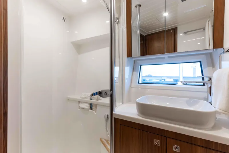 Slide: The Image of Luxurious bathroom in 2025 Riviera 46 Sport Motor Yacht with modern fixtures and window view. - 21