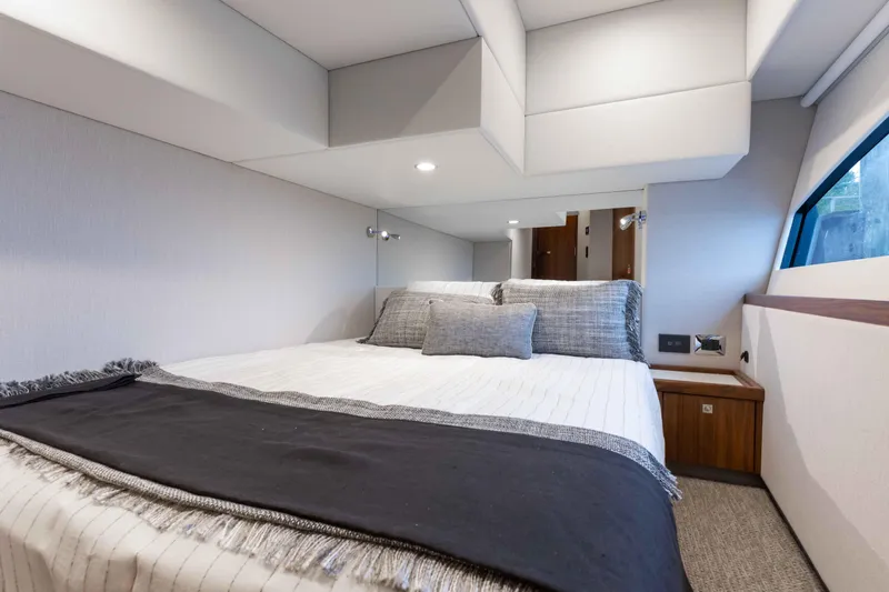Slide: The Image of Interior cabin of 2025 Riviera 46 Sport Motor Yacht, featuring a cozy bed and modern design. - 22