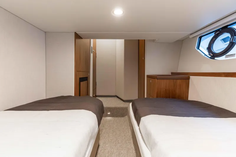 Slide: The Image of Interior cabin of 2025 Riviera 46 Sport Motor Yacht with twin beds and modern decor. - 25