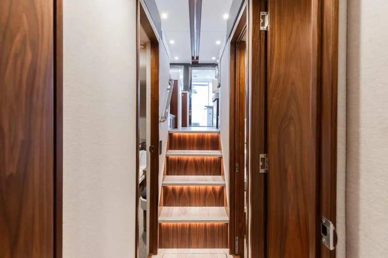Slide: The Image of Interior hallway of 2025 Riviera 46 Sport Motor Yacht with wooden finishes and stairs. - 26