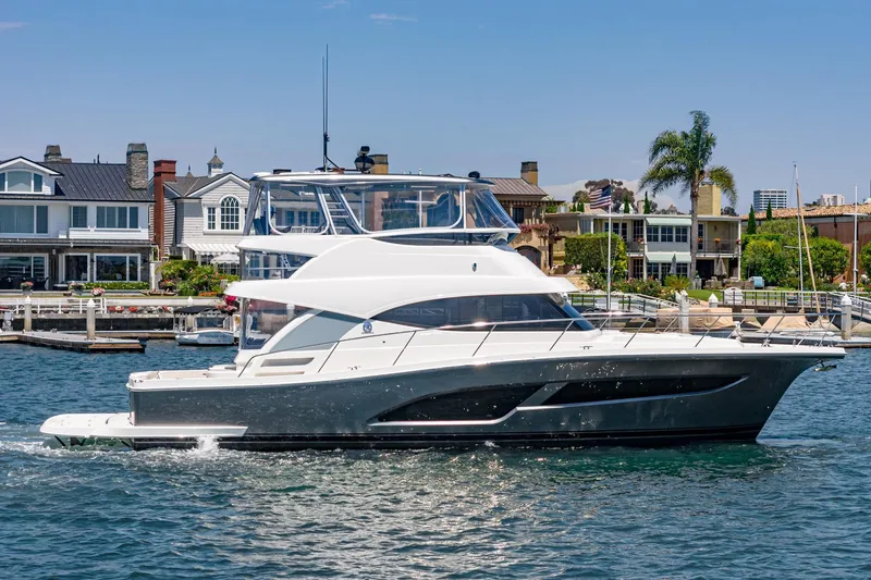 Slide: The Image of 2025 Riviera 46 Sport Motor Yacht cruising near waterfront homes. - 8