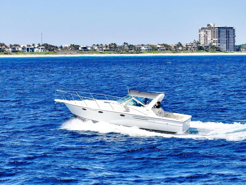 Slide: The Image of 1998 Tiara Yachts 3100 Open cruising on blue ocean near coastal buildings. - 1