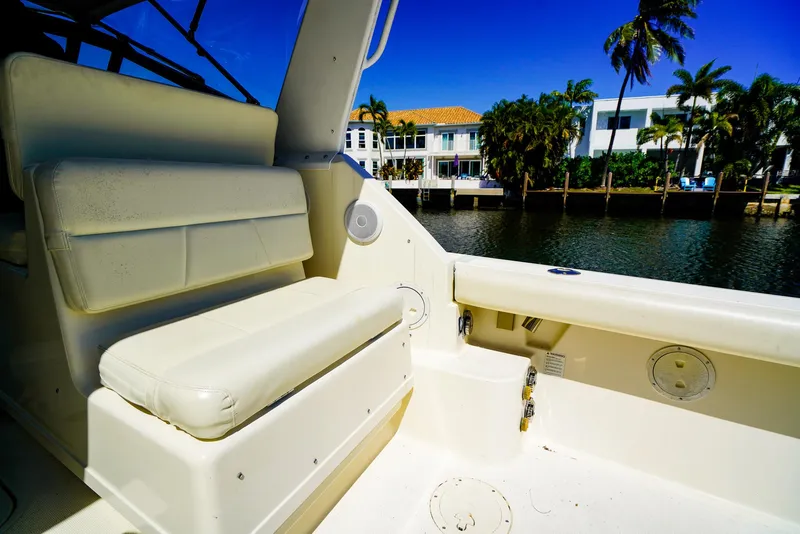 Slide: The Image of 1998 Tiara Yachts 3100 Open interior with white seating, dockside view, and palm trees. - 10