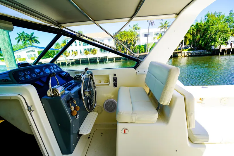 Slide: The Image of 1998 Tiara Yachts 3100 Open cockpit with steering wheel, seating, and waterfront view. - 12