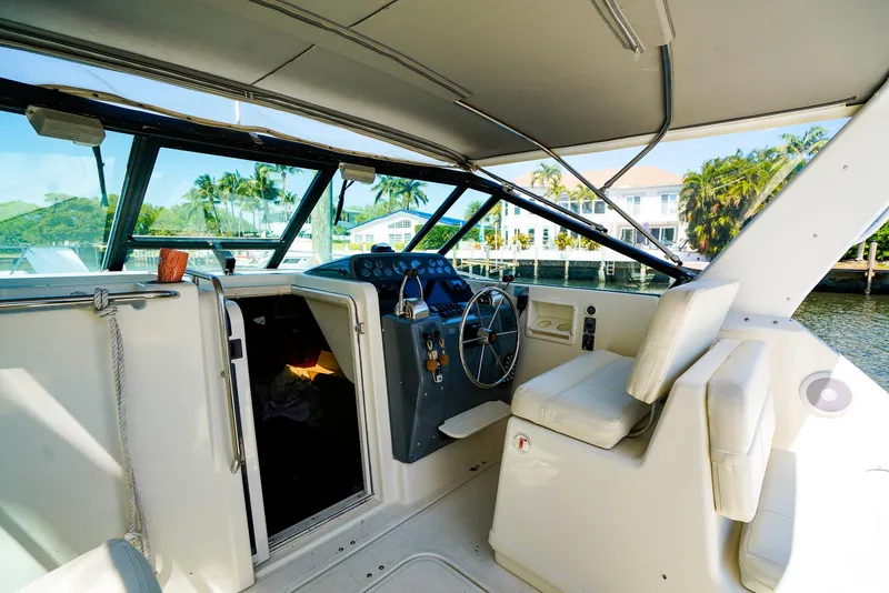 Slide: The Image of 1998 Tiara Yachts 3100 Open cockpit with helm, white seating, and waterfront view. - 14