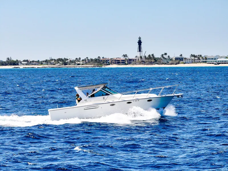 Slide: The Image of 1998 Tiara Yachts 3100 Open cruising on blue ocean near a distant lighthouse. - 2