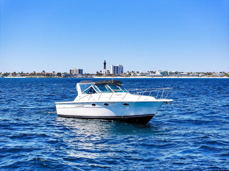 Slide: The Image of 1998 Tiara Yachts 3100 Open cruising on blue ocean near city skyline. - 4
