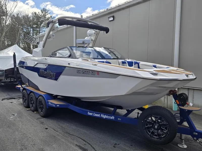 Slide: The Image of 2020 Malibu M240 boat on trailer, parked outdoors near a building. - 10