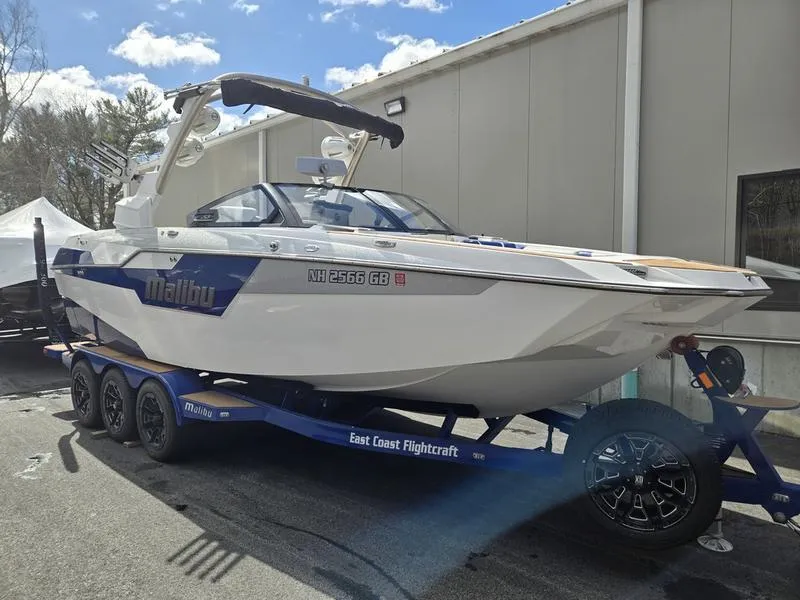 Slide: The Image of 2020 Malibu M240 boat on trailer, parked outdoors near a building. - 11