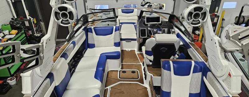 Slide: The Image of 2020 Malibu M240 boat interior with blue and white seating, advanced audio system, and modern dashboard. - 17