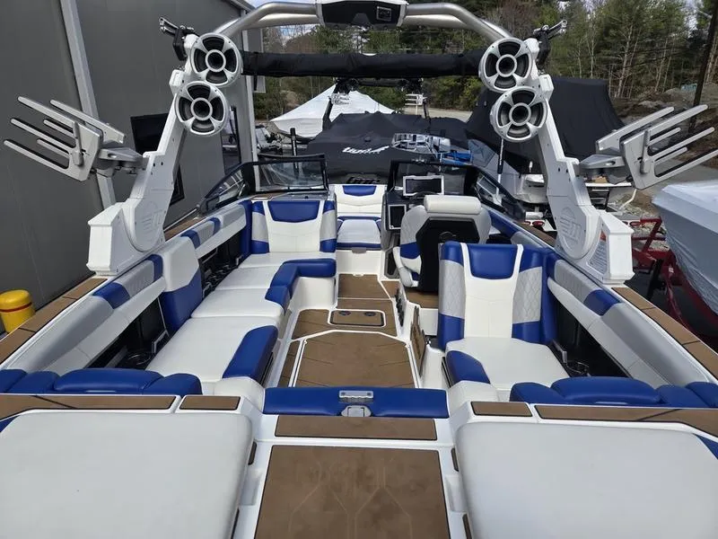 Slide: The Image of 2020 Malibu M240 boat interior with blue and white seating, advanced sound system, and spacious layout. - 22