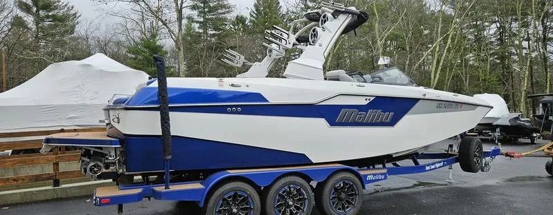 Slide: The Image of 2020 Malibu M240 boat on trailer, blue and white design, parked outdoors. - 3