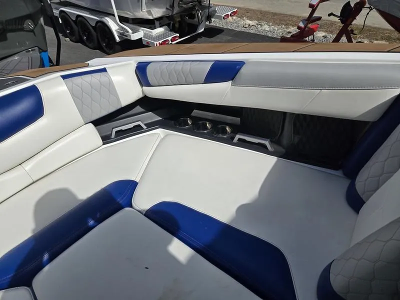Slide: The Image of 2020 Malibu M240 boat interior with white and blue cushioned seating. - 30