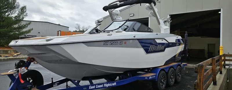 Slide: The Image of 2020 Malibu M240 boat on trailer outside a warehouse. - 6