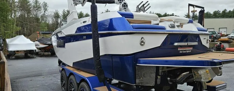 Slide: The Image of 2020 Malibu M240 boat on trailer, blue and white design, parked outdoors. - 7