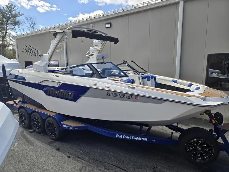 Slide: The Image of 2020 Malibu M240 boat on trailer, parked outdoors near a building. - 9
