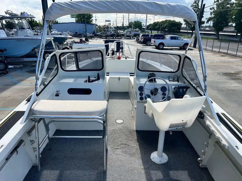 Slide: The Image of 1993 Gravois 23 DC boat interior with steering wheel, seating, and canopy in a parking lot. - 3