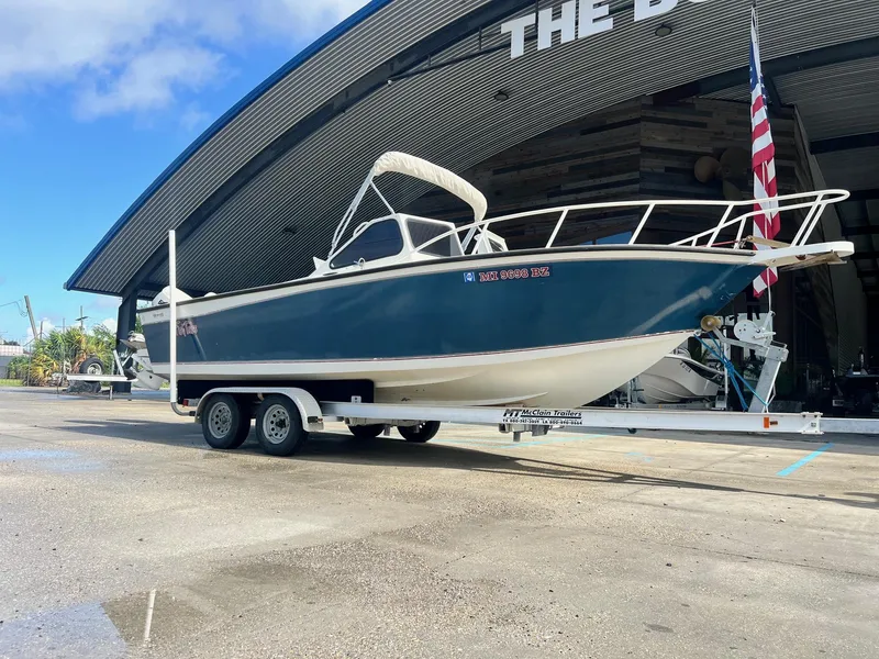 Slide: The Image of 1993 Gravois 23 DC boat on trailer, parked outside a large building with American flag. - 7