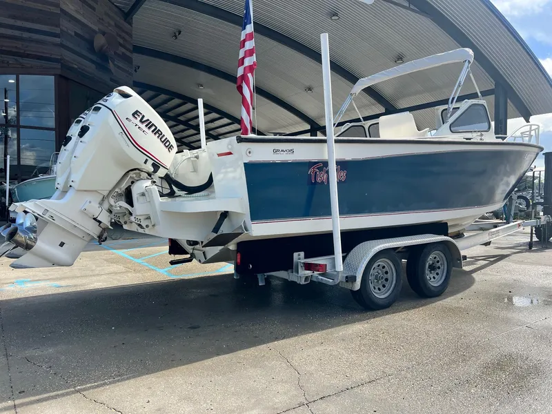 Slide: The Image of 1993 Gravois 23 DC boat on trailer with Evinrude engine, parked outdoors. - 8