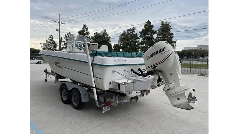 Slide: The Image of 1998 Sunbird 230 CC boat with Evinrude motor, parked outdoors under a clear sky. - 3
