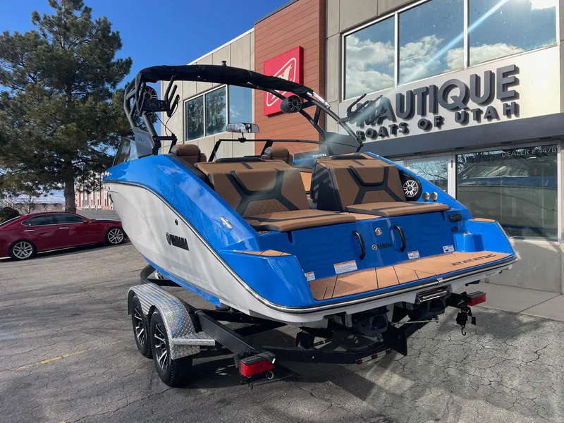 Slide: The Image of 2025 Yamaha Boats 222XE in blue, parked outside dealership. - 3