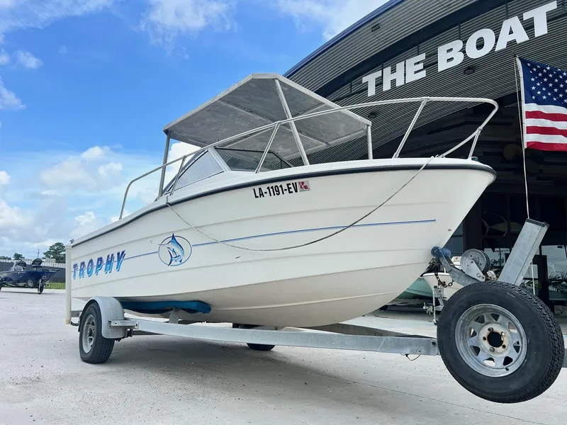 Slide: The Image of 1997 Bayliner 1802 FJ boat with Mercury engine on trailer, parked near American flag. - 2