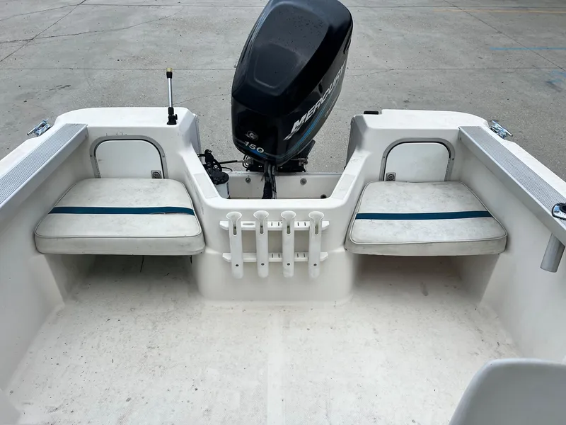 Slide: The Image of 1997 Bayliner 1802 FJ boat with windshield and outboard motor, docked on concrete. - 6