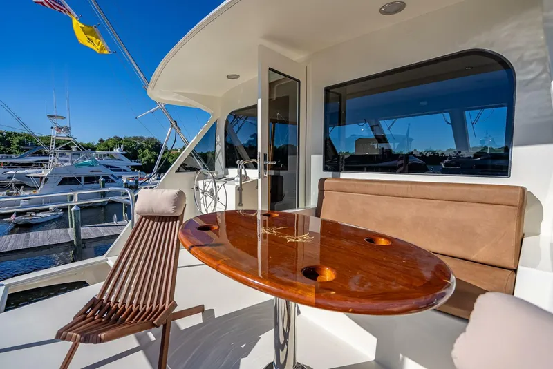 Slide: The Image of 1989 Hatteras 65 Enclosed Bridge yacht with outdoor seating and polished wood table. - 21