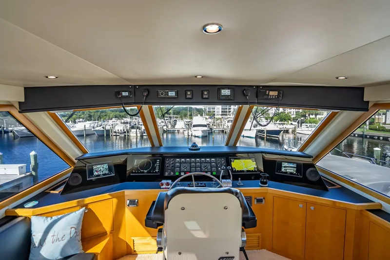 Slide: The Image of Interior view of 1989 Hatteras 65 Enclosed Bridge yacht helm with marina backdrop. - 25