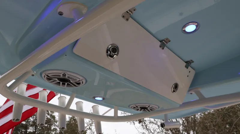Slide: The Image of 2023 Cobia 280 Center Console boat with speakers and rod holders under the T-top. - 14