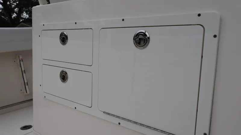 Slide: The Image of 2023 Cobia 280 Center Console storage compartments with sleek white finish. - 22