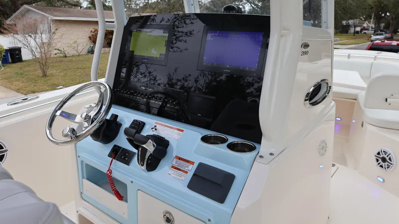 Slide: The Image of 2023 Cobia 280 Center Console boat dashboard with steering wheel and navigation screens. - 9
