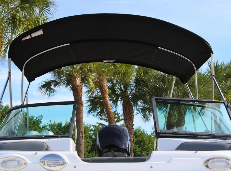 Slide: The Image of 2024 NauticStar DC Deck boat with canopy, palm trees in background. - 10