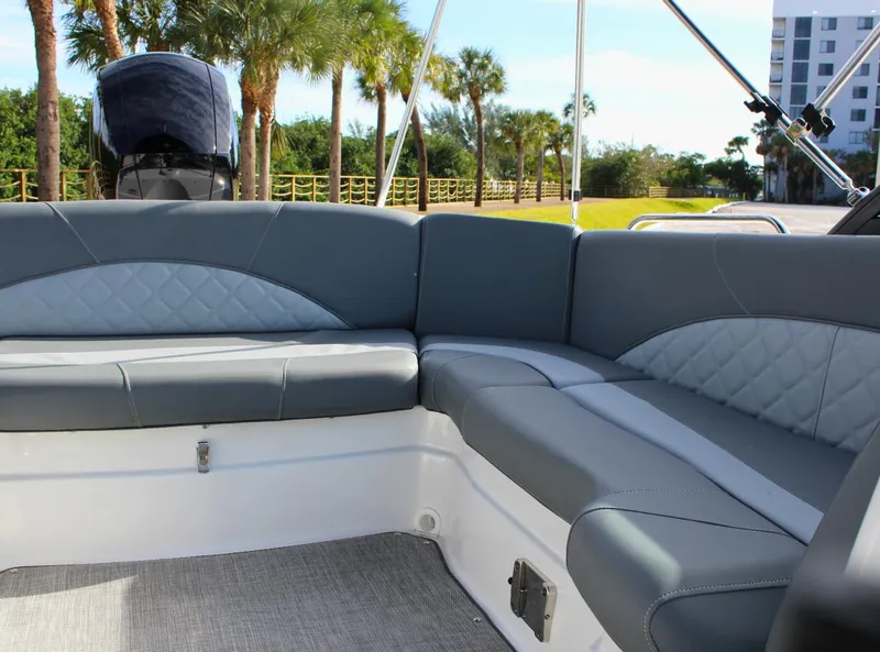 Slide: The Image of 2024 NauticStar DC Deck boat interior with gray seating and palm trees in the background. - 13