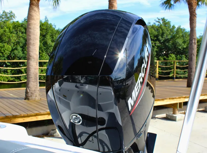 Slide: The Image of 2024 NauticStar DC Deck boat with Mercury outboard engine, docked near palm trees. - 14