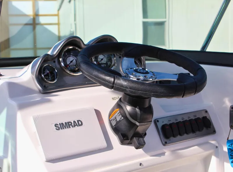 Slide: The Image of 2024 NauticStar DC Deck boat dashboard with steering wheel and Simrad display. - 15