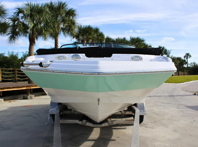Slide: The Image of 2024 NauticStar DC Deck boat on trailer, palm trees in background. - 2