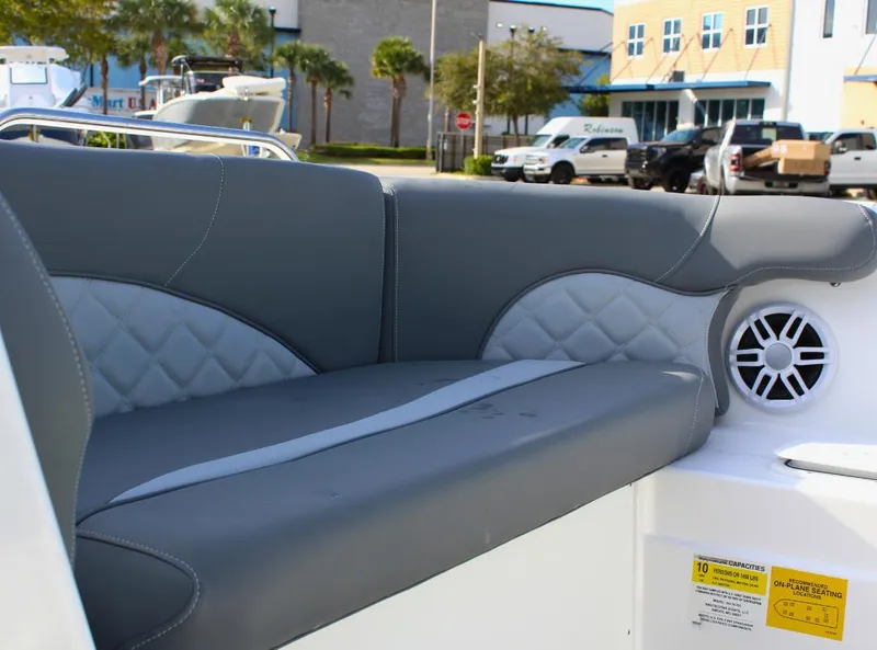 Slide: The Image of 2024 NauticStar DC Deck boat with gray cushioned seating and speaker. - 23