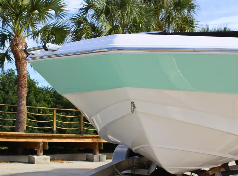 Slide: The Image of 2024 NauticStar DC Deck boat with mint green hull, parked near palm trees. - 6