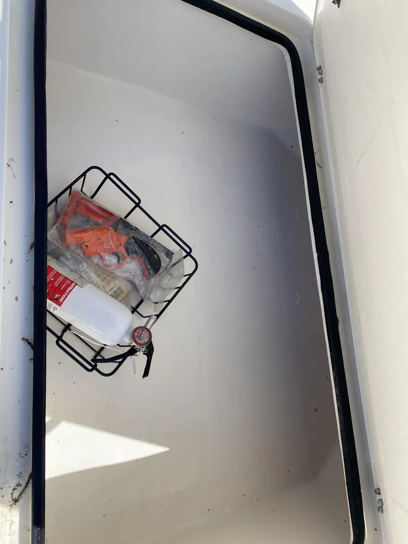 Slide: The Image of Open storage compartment in 2013 ShearWater 25LTZ boat with safety equipment. - 26
